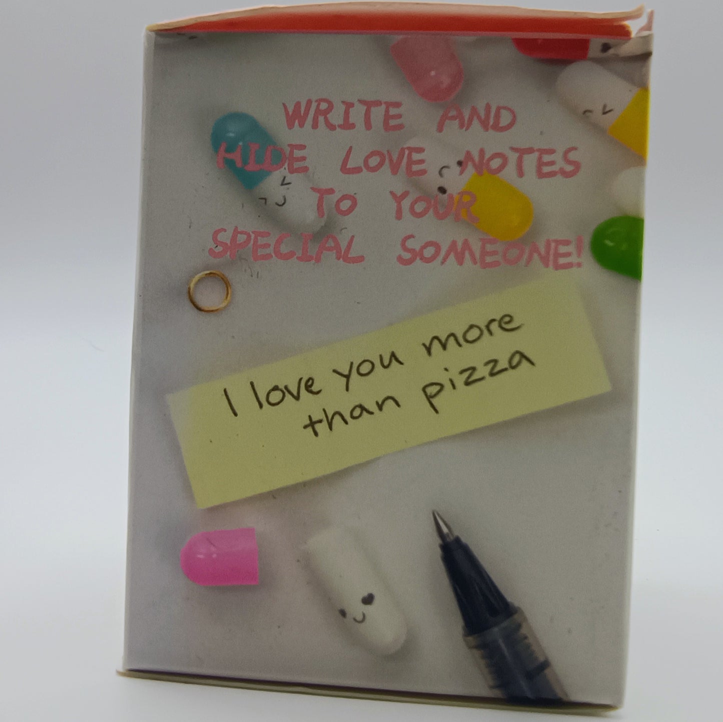 Notebook with a yellow sticky note saying 'I love you more than pizza' and decorative elements on a white background.