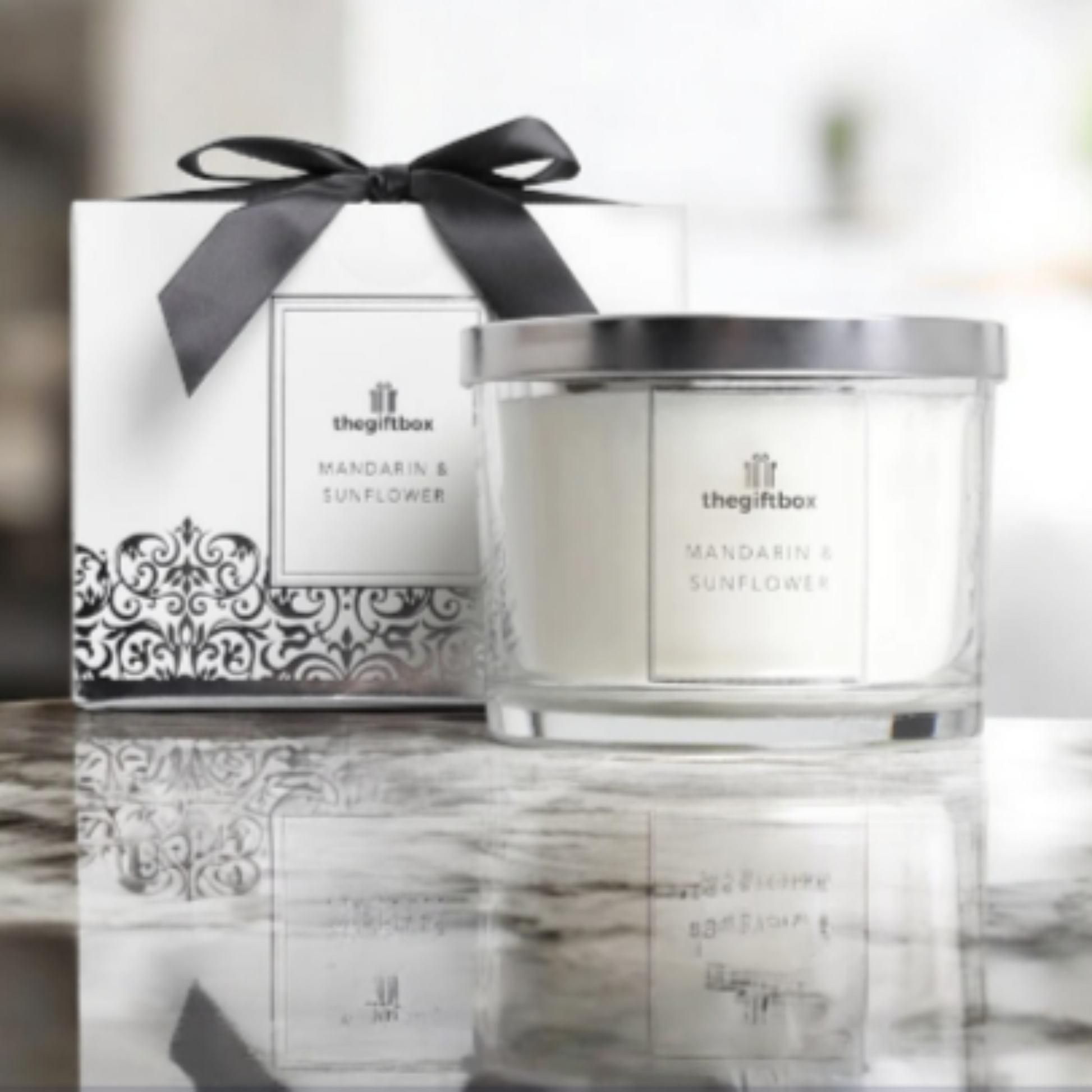 Candle with silver lid and decorative box on a marble surface