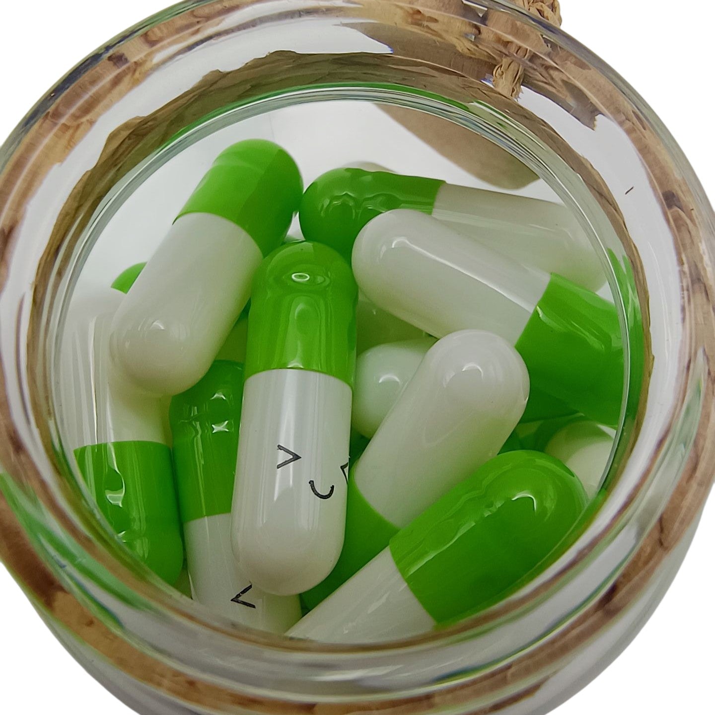 Green and white capsules in a glass jar with wooden lid