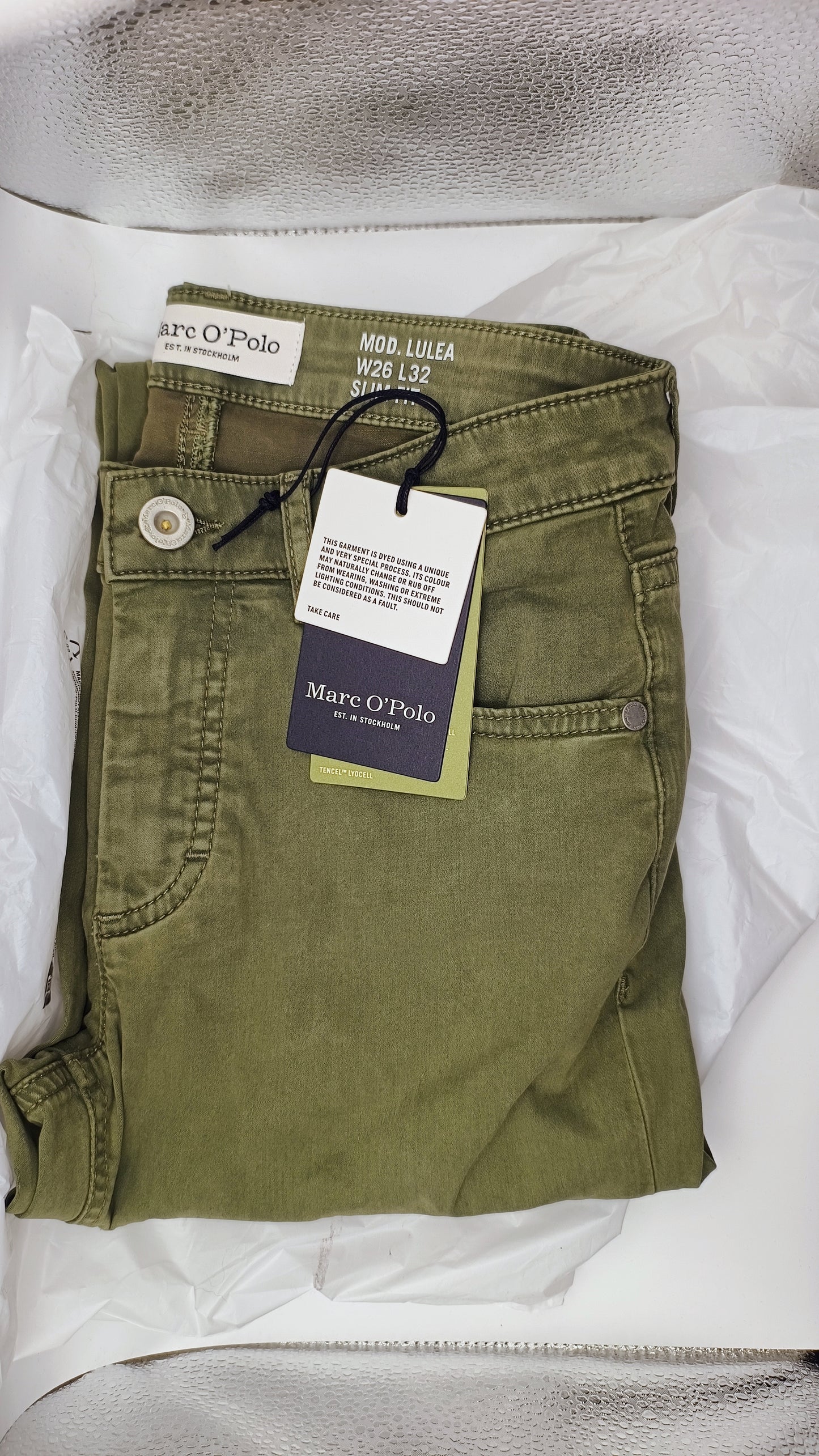 Folded green pants with a Marc O'Polo tag on a white background