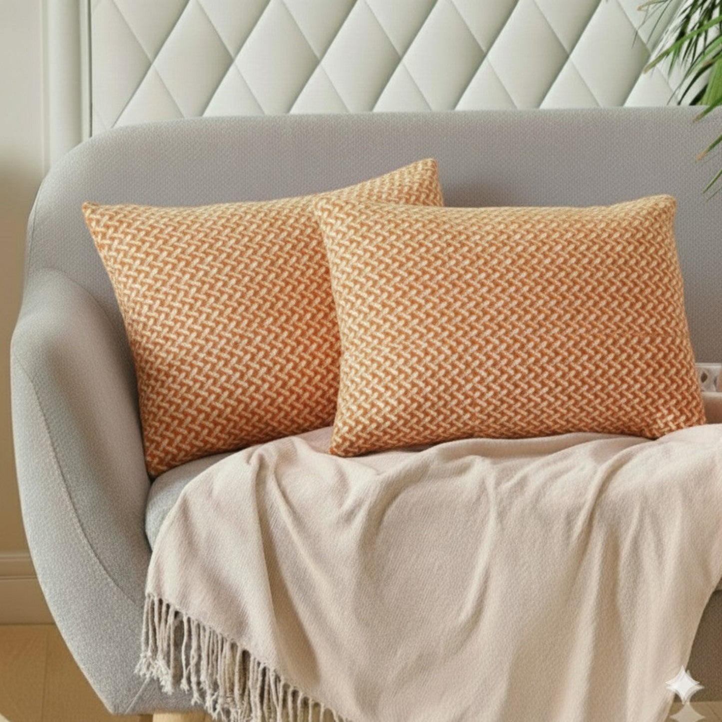 Two orange textured pillows on a gray sofa with a beige blanket