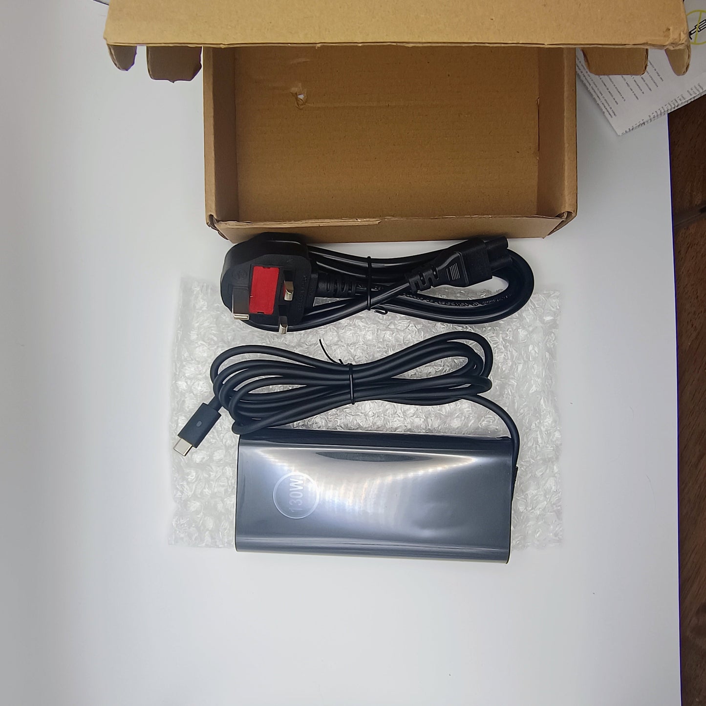 Computer hardware components including a power adapter, cable, and box on a white surface.