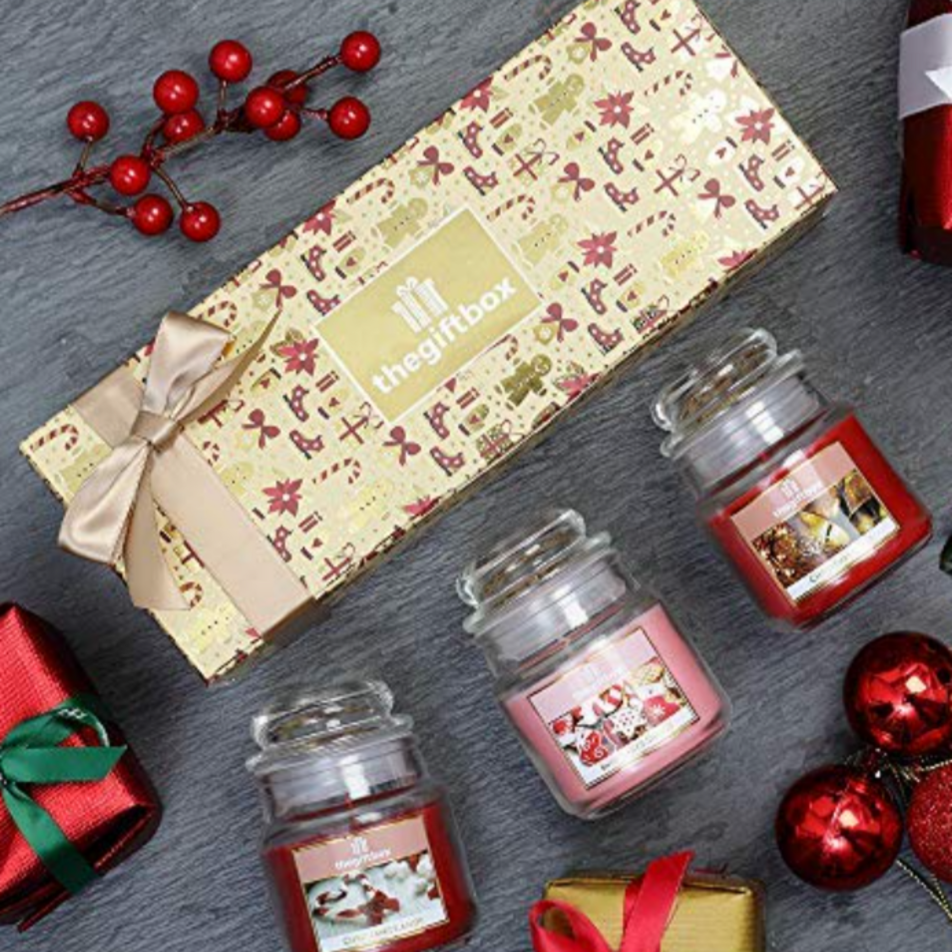Three small jars with festive labels next to a decorative box on a gray surface.