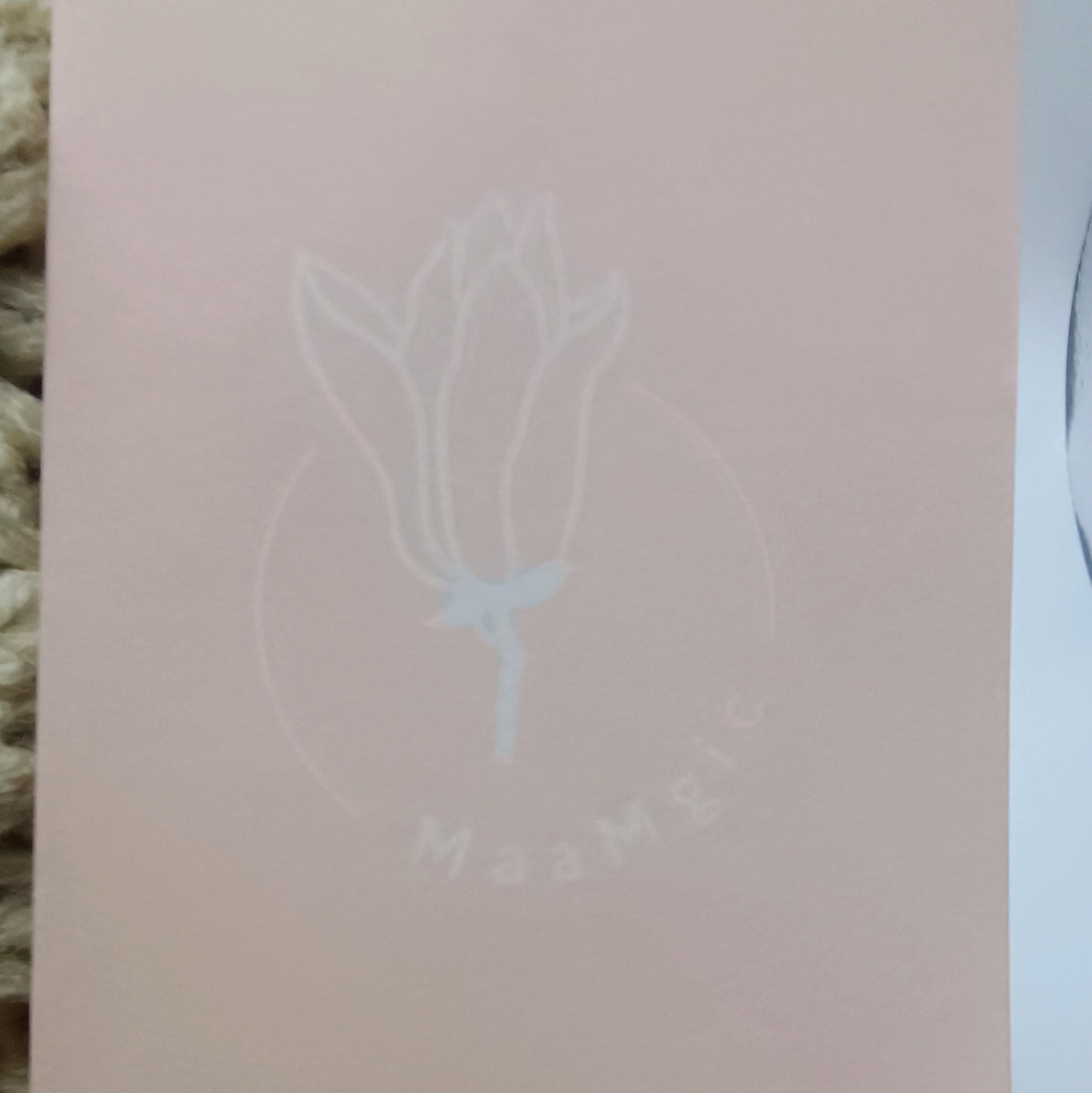 Pink card with a white floral design and text on a textured surface