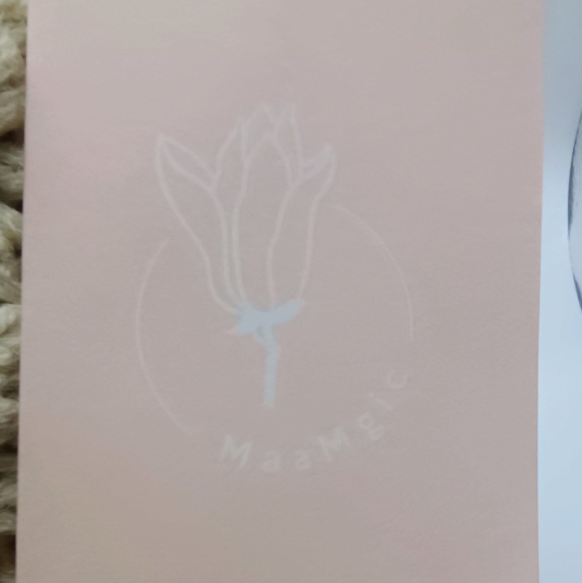 Pink card with a white floral design and text on a textured surface